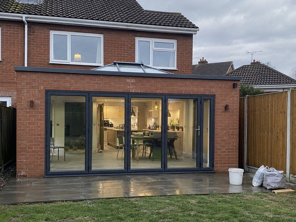 Brick rear extension lit at dusk with a roof lantern and bifold doors