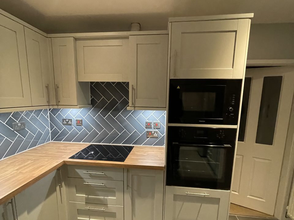 Finished cream shaker kitchen with a blue herringbone splashback
