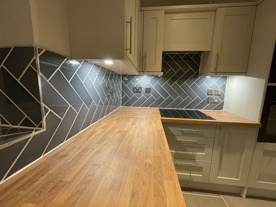Solid wood worktop and herringbone tiled splashback