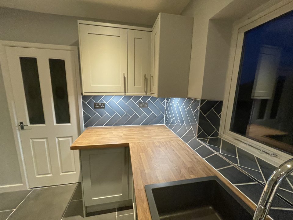 Finished kitchen with cream units set into a bay window