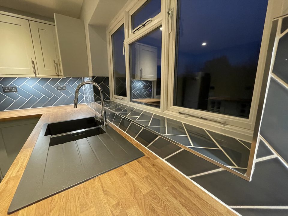 Kitchen sink and window at dusk with a solid wood worktop