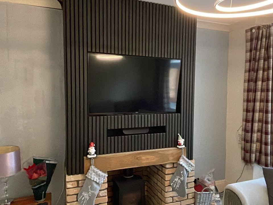 Finished media wall with a slatted panel, television and brick fireplace