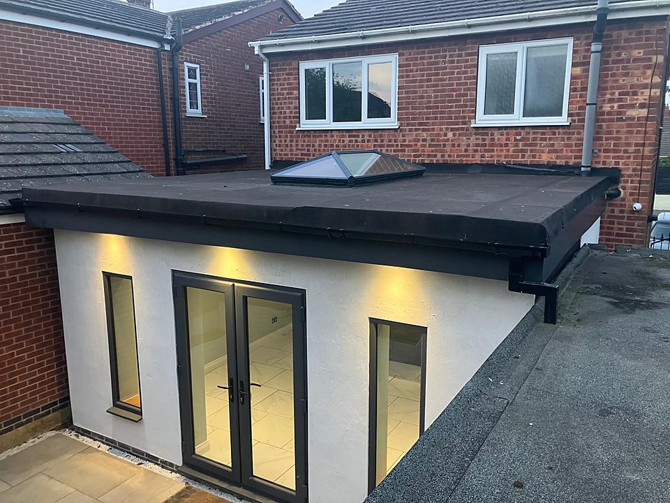 Finished garden room with a flat roof and lantern lit at dusk