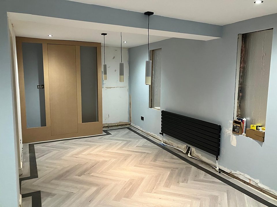Finished room with a herringbone floor and oak door