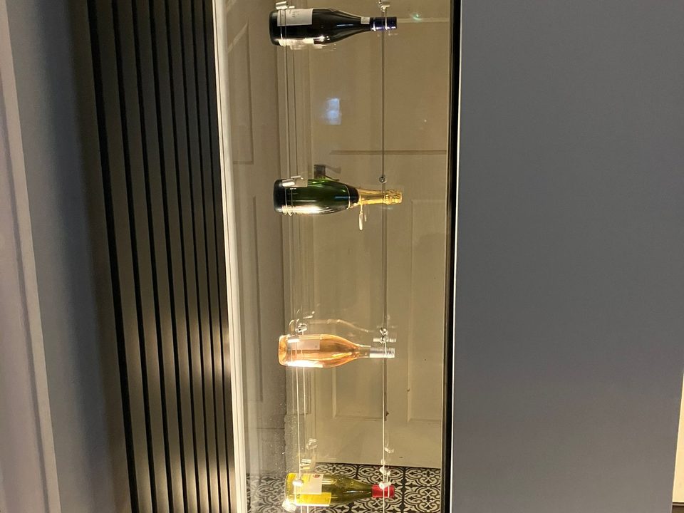 Lit display cabinet built into a dark slatted panel wall